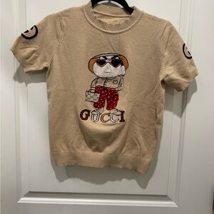 Gucci beige knit top features a cartoon character graphic on the front